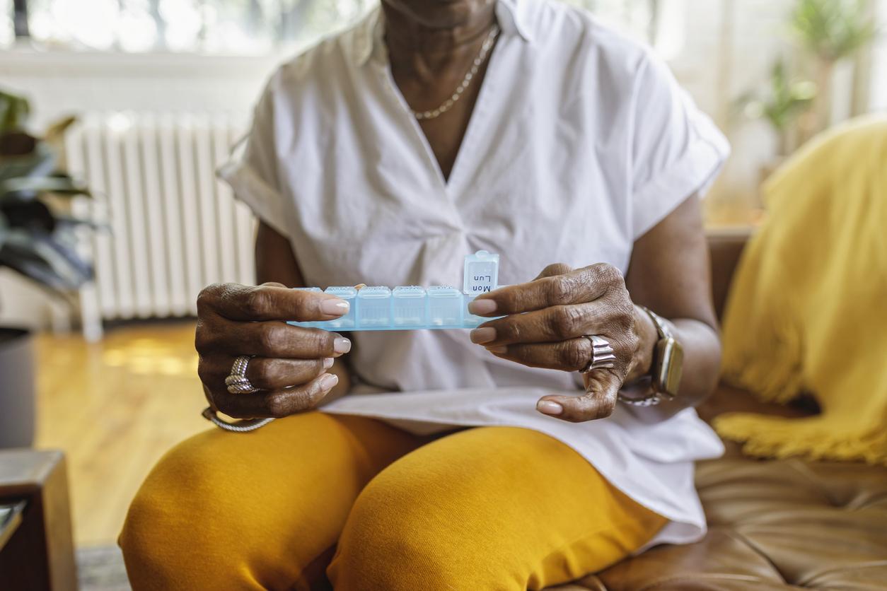 Woman holds a box for weekly pills in her hands. 