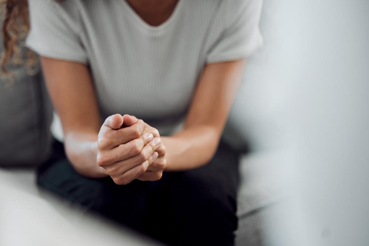 ropped shot of an unrecognisable woman sitting alone and feeling anxious